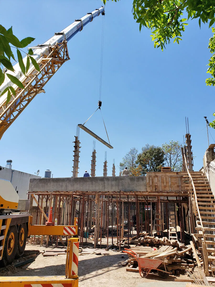 Grúa izando una viga en obra